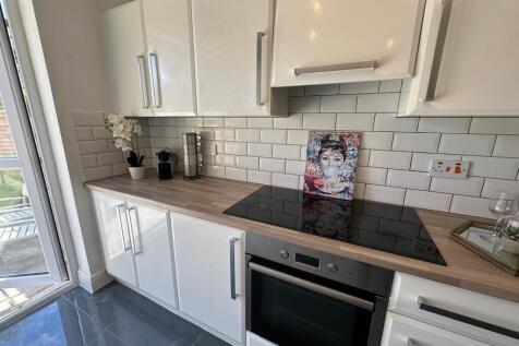 A modern kitchen featuring sleek white cabinetr...