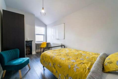 A cozy double bedroom featuring a vibrant yello...