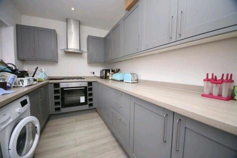 Modern kitchen featuring ample grey cabinetry w...