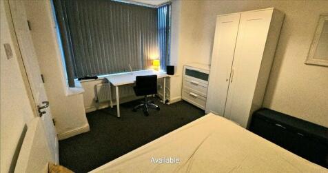 A neat single bedroom featuring a desk with a c...