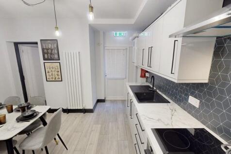 Modern kitchen with sleek white cabinetry, a ma...