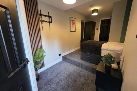A modern single bedroom with a cozy bed raised ...