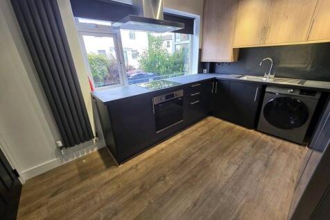 Modern kitchen with sleek black cabinets and wo...