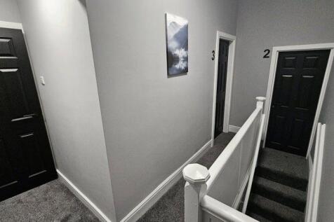 A clean, modern hallway with grey walls and dar...