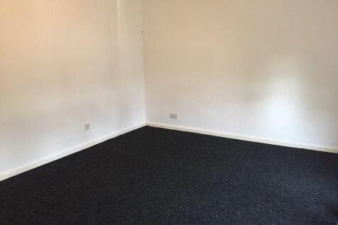A clean empty room with white walls and dark ca...