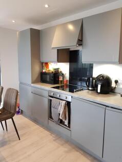 A modern, sleek kitchen with grey cabinetry and...