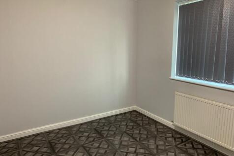 A clean, neutral single bedroom featuring a pat...