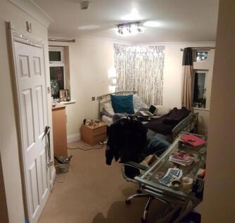 A compact and tidy room featuring a glass desk ...