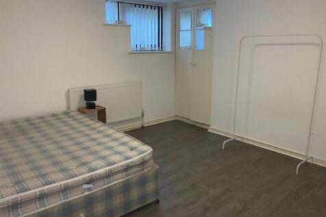 A simple double bedroom with a large mattress, ...