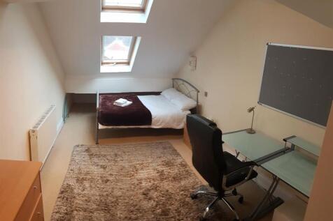 A cozy attic bedroom featuring a single bed pos...