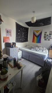 A cozy single bedroom featuring a single bed wi...