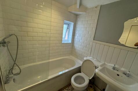 A bright and clean bathroom suite featuring a c...