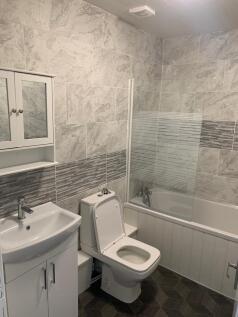 A modern bathroom suite featuring a white sink ...