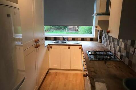 A compact kitchen featuring white cabinetry wit...