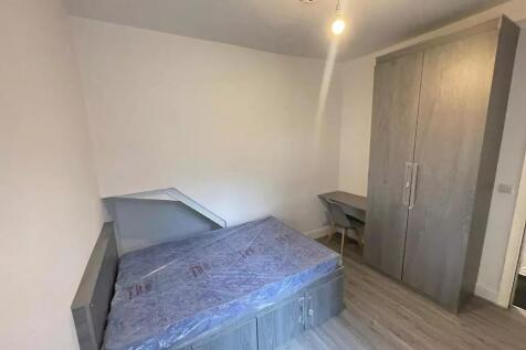 A tidy single bedroom featuring a modern grey s...