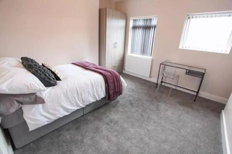 A neat and well-lit single bedroom featuring a ...