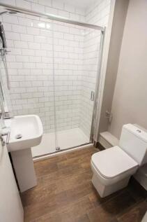 A modern, clean bathroom featuring a glass-encl...