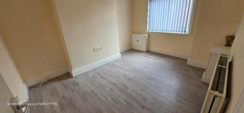 A clean and bright single bedroom featuring woo...