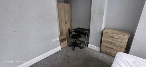 A modest bedroom featuring a single bed with a ...
