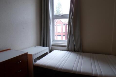 A cozy single bedroom featuring a large window ...