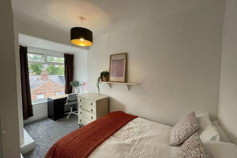 A cozy bedroom featuring a neatly made bed with...