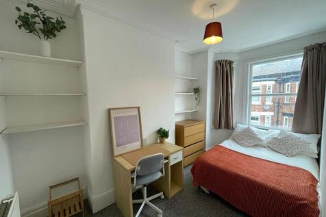 A cozy single bedroom featuring a large window ...