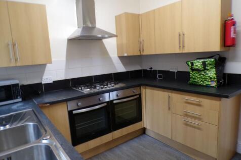 Modern kitchen featuring wooden cabinets, a sta...