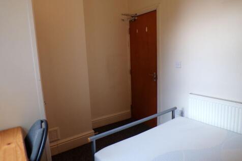 A simple, tidy bedroom featuring a single bed w...