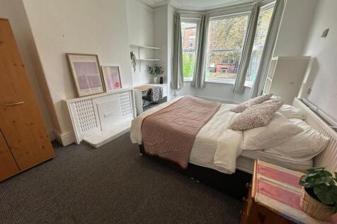A bright and welcoming bedroom with a large bay...