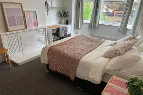 A bright and welcoming bedroom featuring a comf...