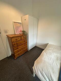 A cozy and tidy single bedroom featuring a smal...