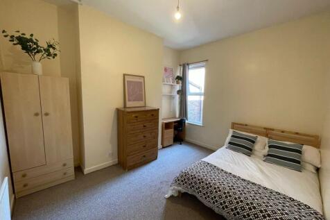 A bright and welcoming bedroom featuring a comf...