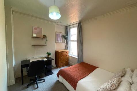 A bright and cozy bedroom featuring a comfortab...