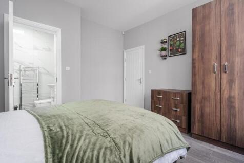 This inviting double bedroom features a plush g...