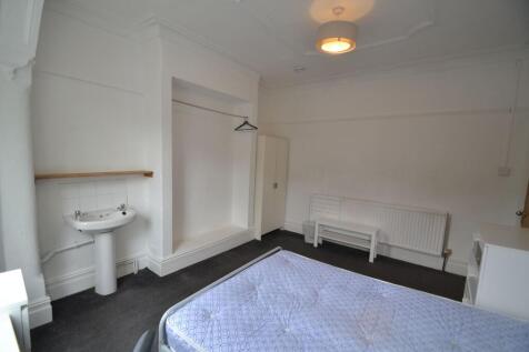 A simple, clean single bedroom featuring a bed ...