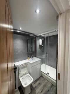Modern bathroom featuring a sleek white toilet,...