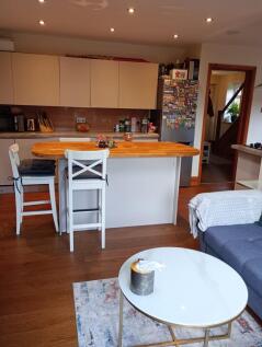 A cozy living room featuring a modern kitchen i...