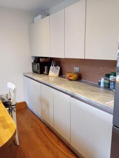 A modern kitchen with white cabinetry and a pol...