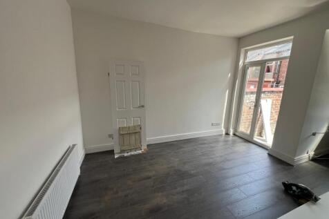 A bright double bedroom featuring dark wood flo...