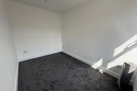 A clean and bright single bedroom with a dark c...