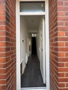 A narrow, clean hallway with dark flooring and ...