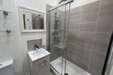A modern bathroom featuring a glass-enclosed sh...