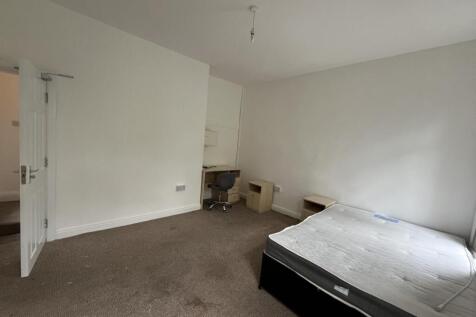 A simple, well-lit single bedroom with a bed an...