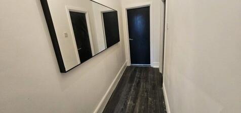 A clean and modern hallway with dark wood floor...