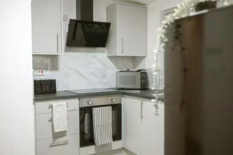 Modern kitchen featuring sleek white cabinetry,...