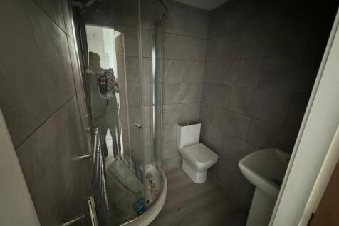 A modern bathroom featuring a curved glass show...
