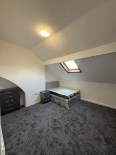 A cozy attic bedroom with a skylight window, a ...