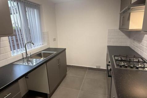 A modern, well-lit kitchen with sleek counterto...