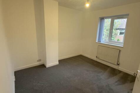 A tidy, well-lit bedroom with a window allowing...
