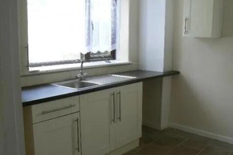 A bright and tidy kitchen with white cabinets, ...